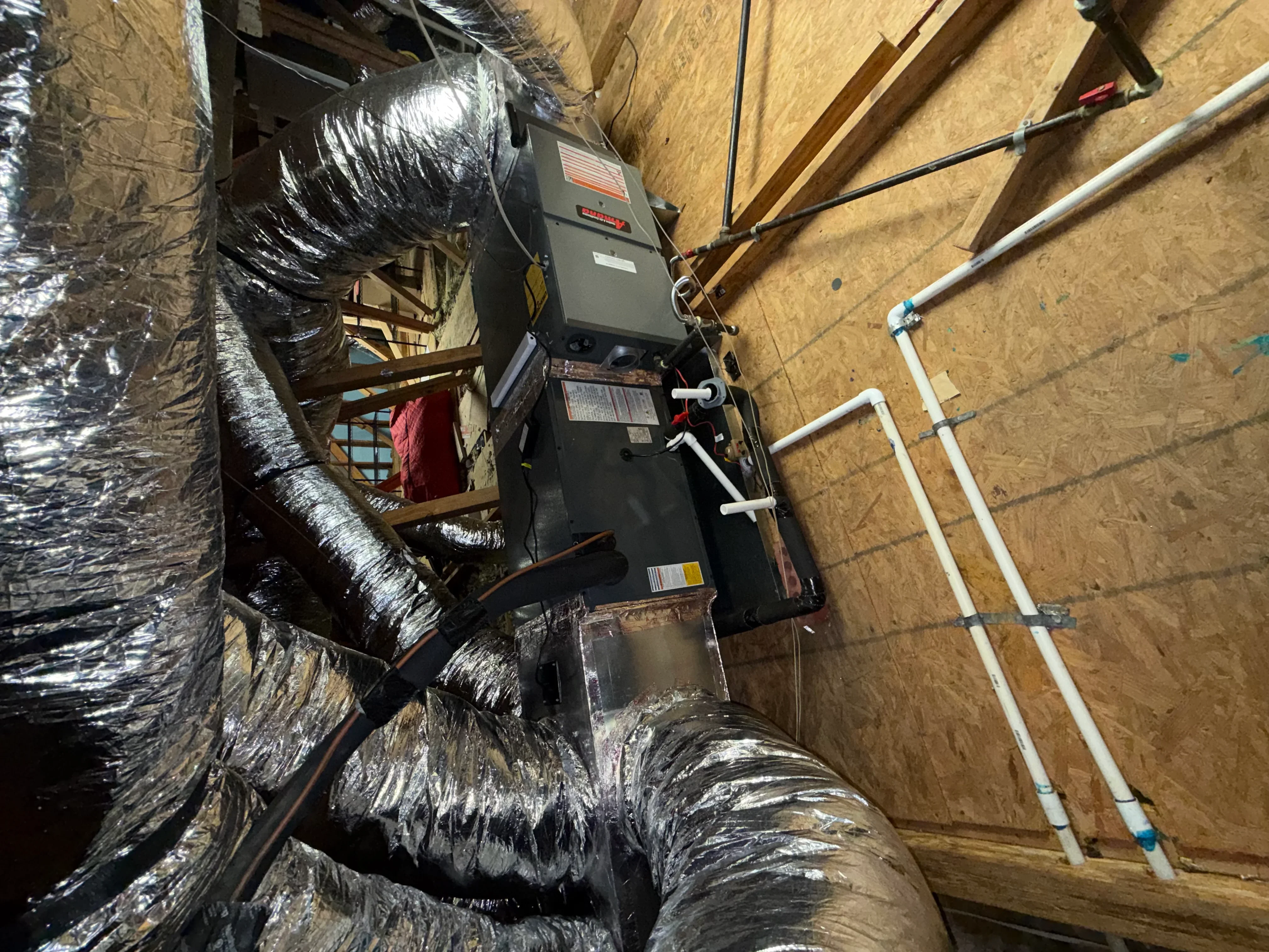 Furnace unit with insulated ductwork and PVC condensate lines in attic installation