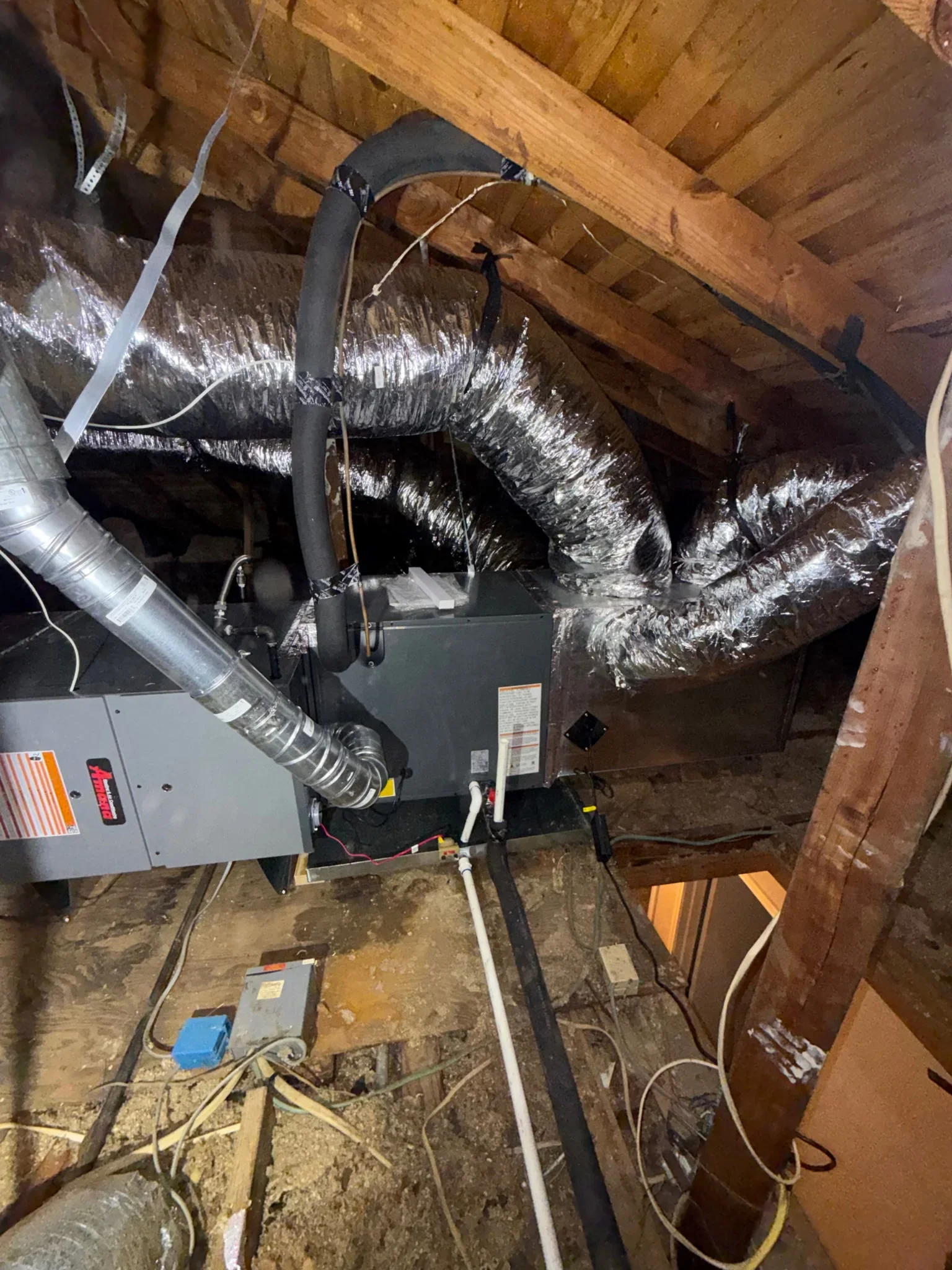 Furnace unit with insulated flex ductwork installed in attic space with wooden beams