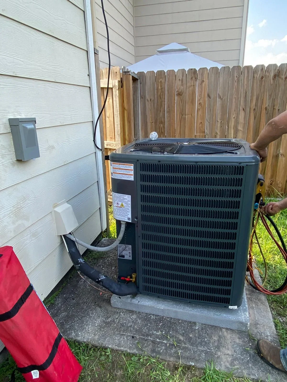 New AC condenser unit installed on concrete pad with refrigerant lines connected to home
